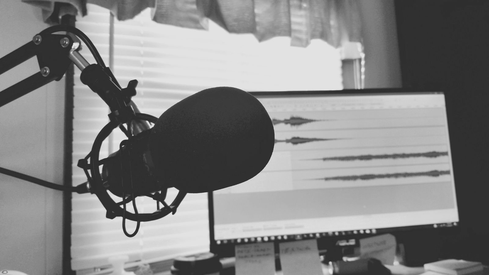 Instrutor em estúdio de podcast, sentado diante de microfones profissionais durante uma gravação