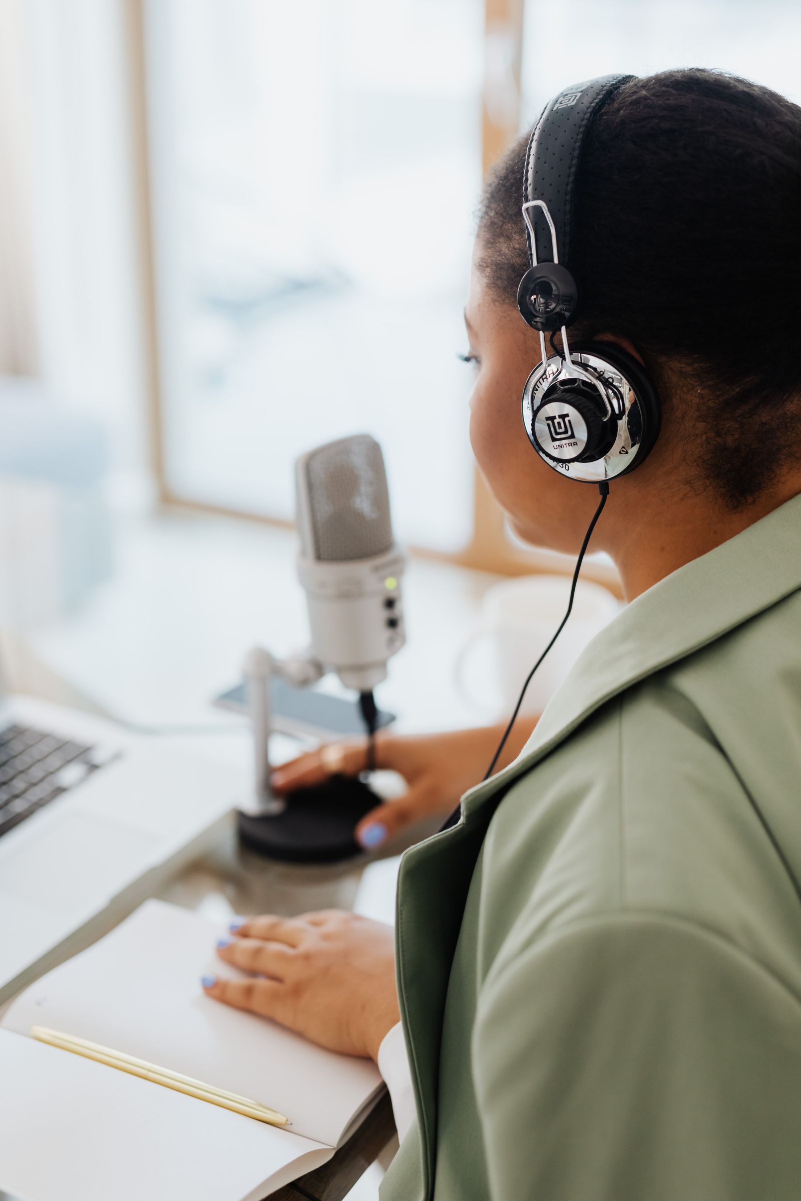 Instrutora conversando em um estúdio de podcast equipado com mesa de som e microfones